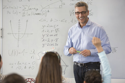 Lächelnder männlicher Lehrer für Naturwissenschaften, der eine Unterrichtsstunde am Whiteboard im Klassenzimmer leitet - CAIF04381