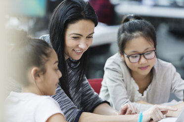 Lehrerin und Schülerin benutzen Laptop im Klassenzimmer - CAIF04385