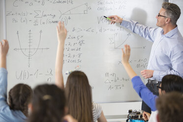 Männlicher Lehrer leitet eine Physikstunde am Whiteboard im Klassenzimmer - CAIF04386