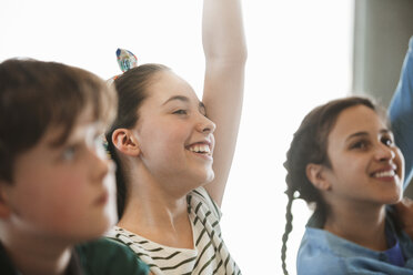 Smiling, eager girl student asking a question in classroom - CAIF04387