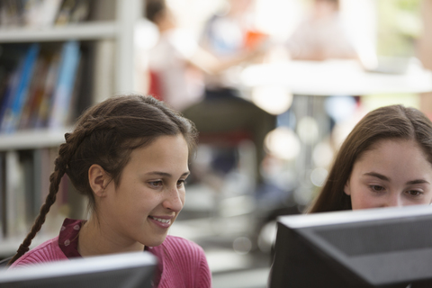 Girl students researching, using computer in library stock photo