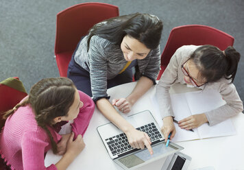 Lehrerin hilft Schülerin bei der Recherche am Laptop am Bibliothekstisch - CAIF04409