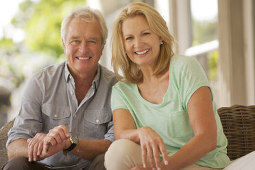 Porträt eines lächelnden Paares auf einer Terrasse - CAIF04442