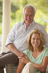 Portrait of smiling couple holding hands on patio - CAIF04453