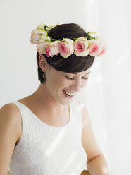 Smiling bride wearing rose wreath on head - CAIF04483