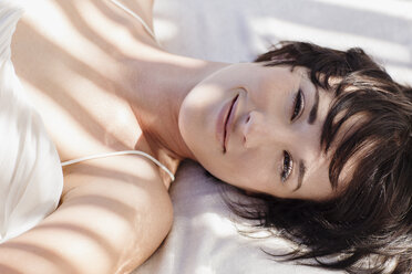 Portrait of smiling woman laying in bed - CAIF04484