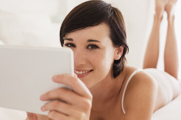 Nahaufnahme einer lächelnden Frau, die ein digitales Tablet benutzt - CAIF04504