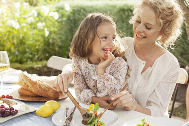 Mutter und Tochter essen im Garten - CAIF04532