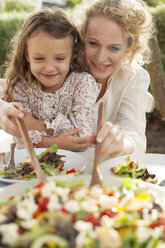 Mutter und Tochter essen im Garten - CAIF04533