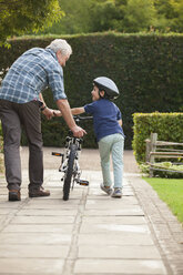 Großvater und Enkel schieben das Fahrrad auf dem Bürgersteig - CAIF04539