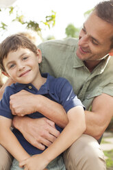 Father and son hugging outdoors - CAIF04542