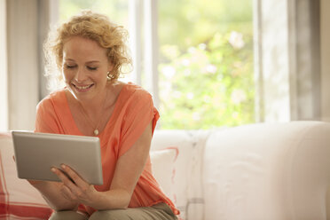 Frau benutzt digitales Tablet auf Sofa - CAIF04545