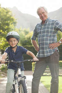 Älterer Mann bringt seinem Enkel das Fahrradfahren bei - CAIF04552