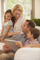 Family using digital tablet on sofa - CAIF04554