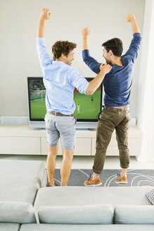 Men cheering and watching soccer game - CAIF04580