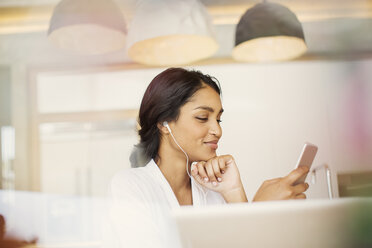 Woman with headphones listening to music on mp3 player - HOXF00247