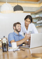 Couple texting with cell phone at laptop - HOXF00252