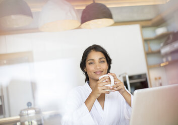 Porträt selbstbewusste Frau im Bademantel trinkt Kaffee am Laptop - HOXF00258