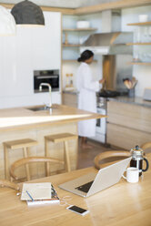 Laptop, French press coffee, cell phone and notebook on kitchen table - HOXF00260