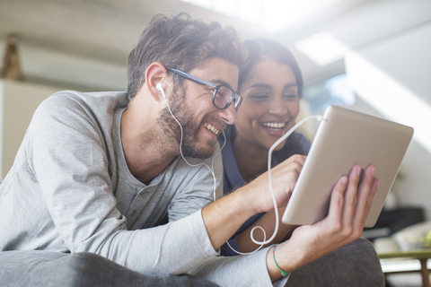 Lächelndes Paar mit Kopfhörern und digitalem Tablet, lizenzfreies Stockfoto