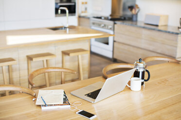 Laptop, French press coffee, cell phone and notebook on kitchen table - HOXF00305