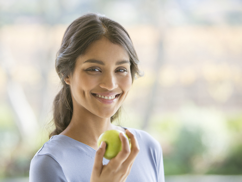 Close up portrait smiling woman eating green apple stock photo