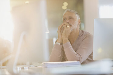 Konzentrierter Geschäftsmann arbeitet am Computer in einem sonnigen Büro - HOXF00362