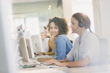 Portrait smiling businesswoman with headset working at computer in office - HOXF00405