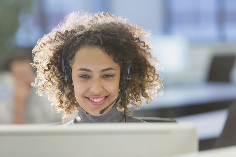 Businesswoman with headset working at computer in office stock photo