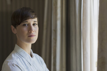 Portrait confident brunette woman at window - HOXF00454