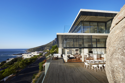 Modernes luxuriöses Haus und Terrasse mit Meerblick unter sonnigem blauem Himmel, lizenzfreies Stockfoto