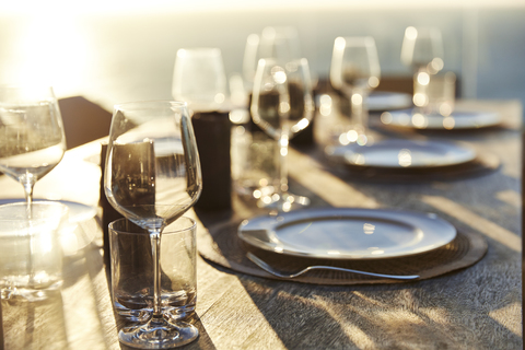 Sun shining over placesettings on wooden table stock photo