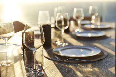 Sun shining over placesettings on wooden table - HOXF00466