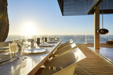 Die Sonne scheint über dem Meer hinter dem luxuriösen Esstisch auf der Terrasse mit Sitzgelegenheiten - HOXF00468