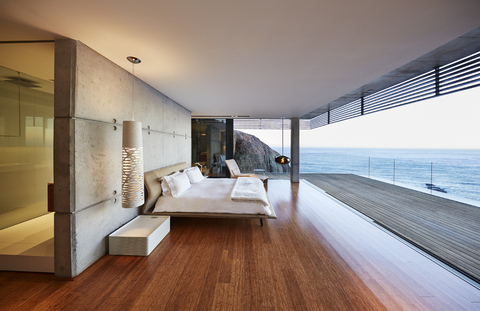 Modernes, luxuriöses Schlafzimmer mit Zugang zur Terrasse und Meerblick, lizenzfreies Stockfoto