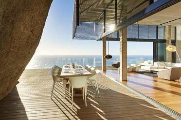 Modern luxury dining table on sunny patio with ocean view - HOXF00470