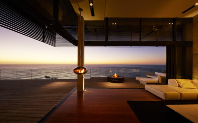 Fire pit and hanging fireplace on modern luxury patio with sunset ocean view - HOXF00471