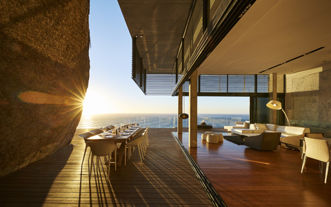 Sonnenuntergang hinter dem modernen Luxus-Terrassentisch mit Meerblick, lizenzfreies Stockfoto