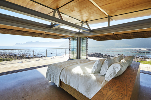 Modernes, luxuriöses Bett mit Zugang zur Terrasse und sonnigem Meerblick, lizenzfreies Stockfoto