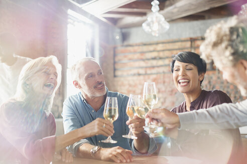 Freunde stoßen mit Weißweingläsern am Restauranttisch an - HOXF00509