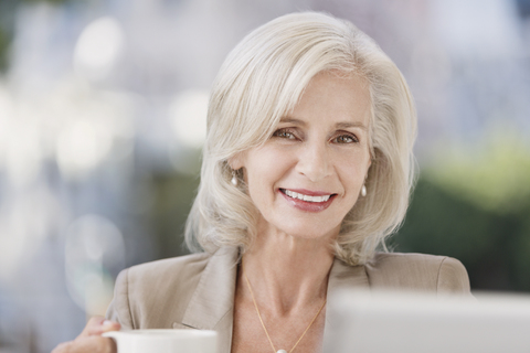 Porträt einer lächelnden älteren Geschäftsfrau beim Kaffeetrinken, lizenzfreies Stockfoto