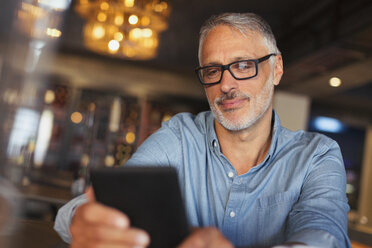 Mann schreibt im Restaurant eine SMS mit dem Handy - HOXF00512