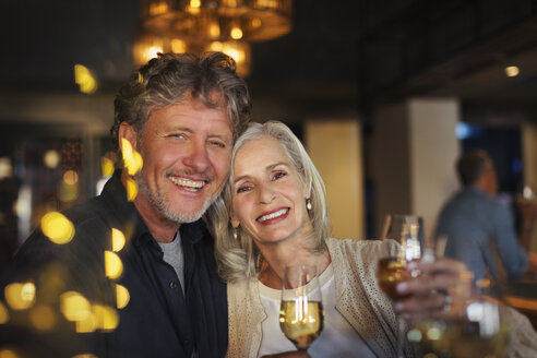 Portrait lächelndes älteres Paar stößt mit Weißweingläsern in einer Bar an - HOXF00528
