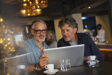 Männer benutzen Laptop im Restaurant - HOXF00530