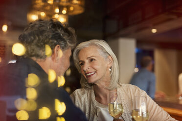 Affectionate smiling senior couple drinking white wine in bar - HOXF00535