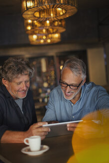Männer, die ein digitales Tablet benutzen und am Restauranttisch Kaffee trinken - HOXF00541