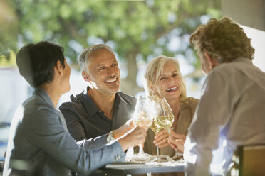 Couples toasting white wine glasses at sunny restaurant table - HOXF00542