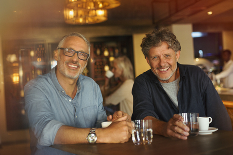 Portrait lächelnde Männer trinken Kaffee und Wasser am Restauranttisch, lizenzfreies Stockfoto