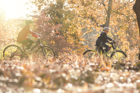 Junge und Mädchen fahren Fahrrad im Herbstlaub - HOXF00556