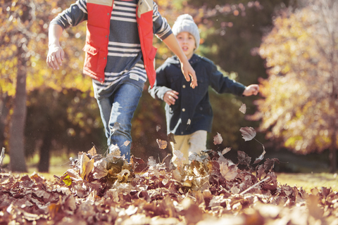 Jungen laufen im Herbstlaub, lizenzfreies Stockfoto